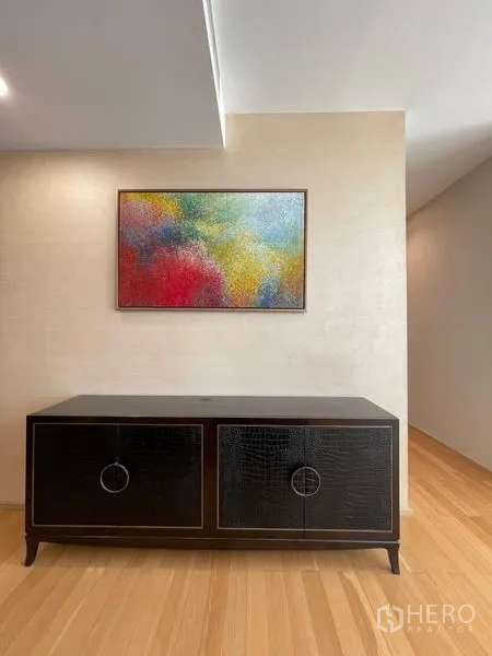 Condominium for rent in Watthana, Bangkok - Hallway with black console cabinet and colorful abstract artwork.