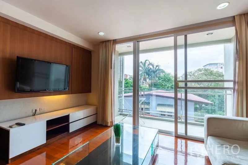 公寓 出租在Watthana, Bangkok - 客厅挂墙电视与落地窗通向阳台