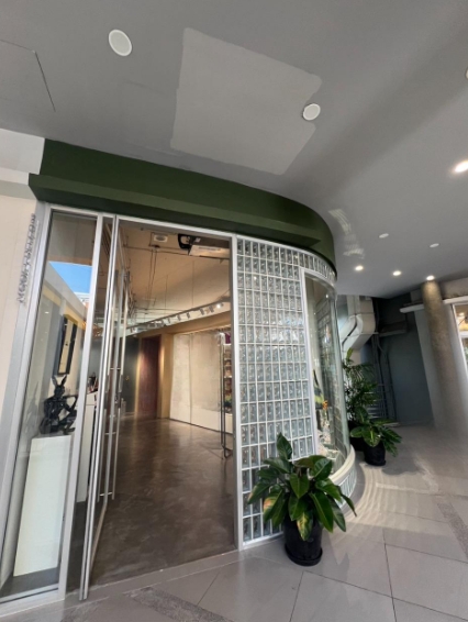 Retail Space for rent in Khlong Toei, Bangkok - Entrance with full-height glass doors, glass-block wall, and open-plan interior near the escalator.