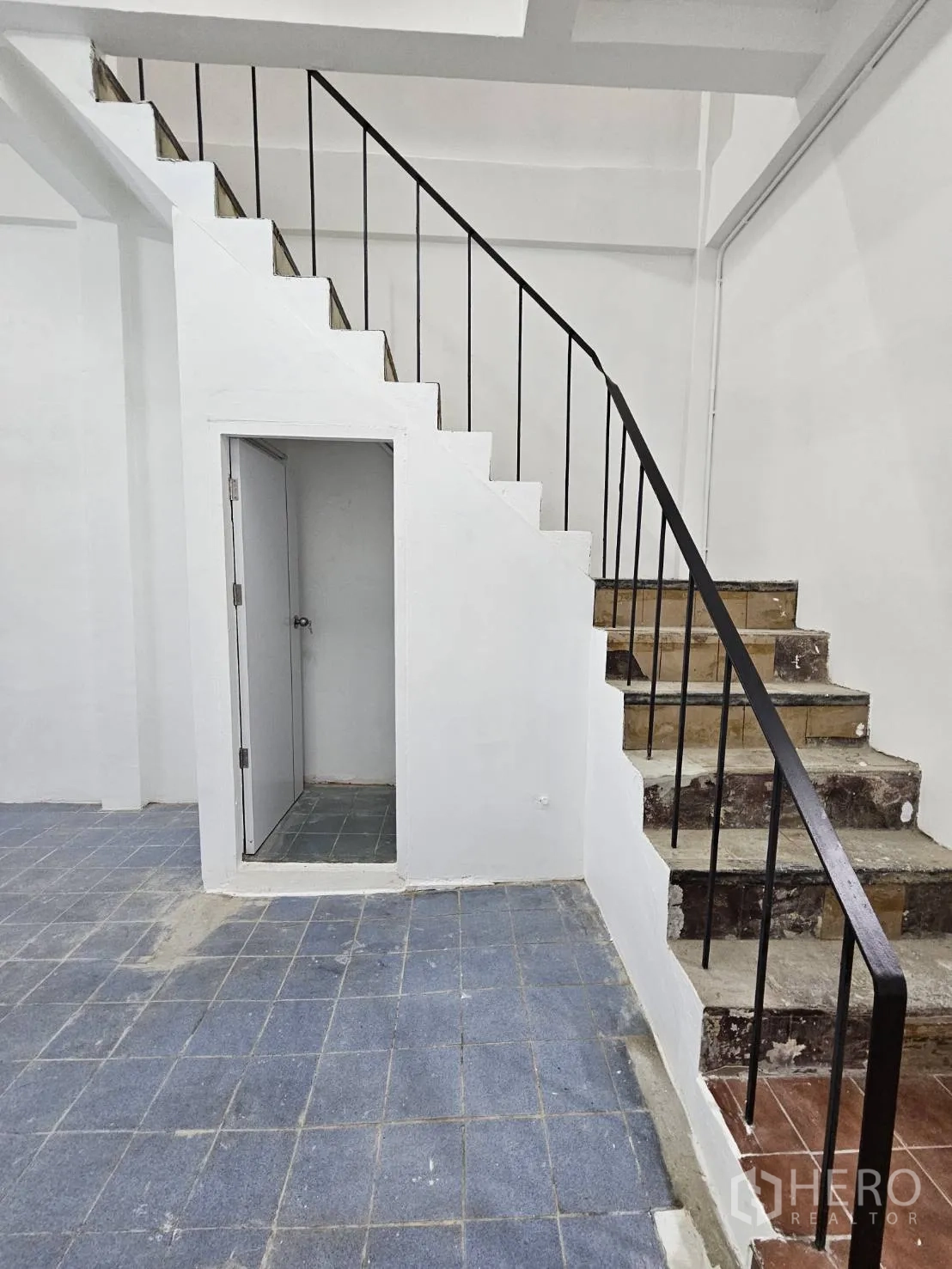 Home Office for rent in Khlong Toei, Bangkok - Staircase with black metal railing and a storage room beneath.