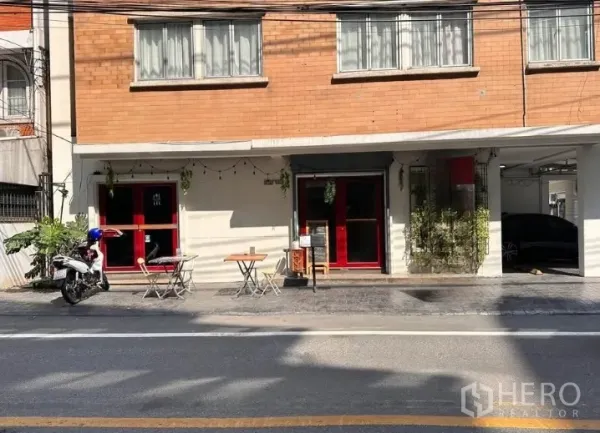 Retail Space for rent in Watthana, Bangkok - Street-facing retail frontage with red doors, outdoor seating, and covered parking in Watthana, Bangkok.