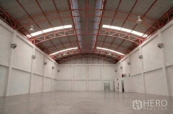 Factory for rent in Phra Samut Chedi, Samut Prakan - Spacious warehouse hall with arched metal roof, skylight strips, and industrial pendant lights.