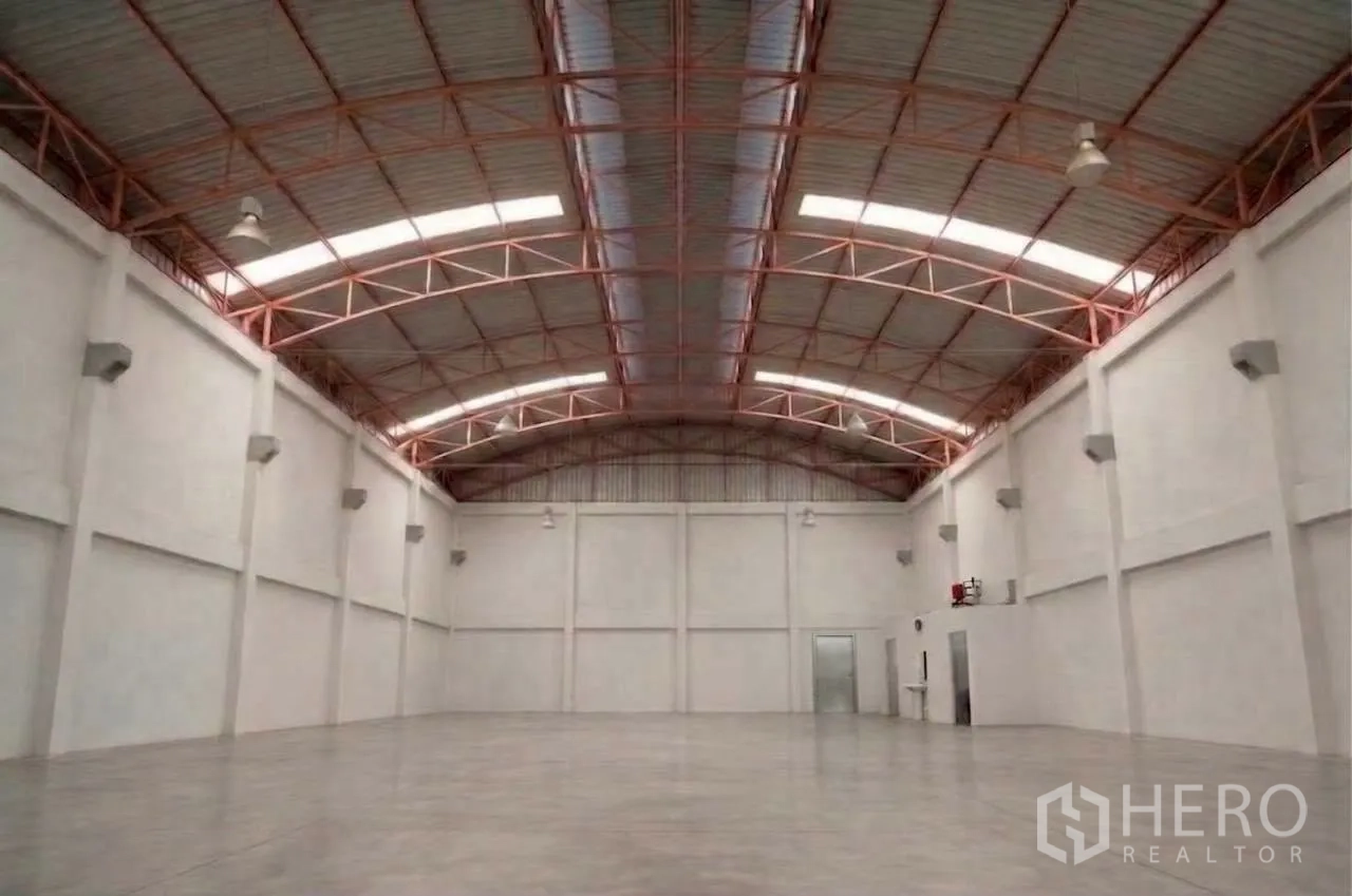 Factory for rent in Phra Samut Chedi, Samut Prakan - Spacious warehouse hall with arched metal roof, skylight strips, and industrial pendant lights.
