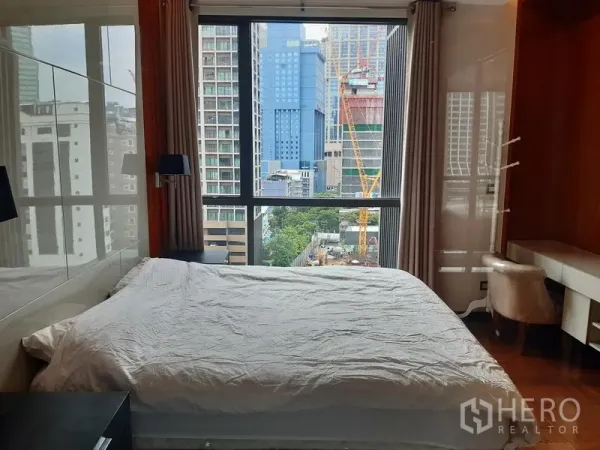 Condominium for rent in Khlong Toei, Bangkok - Bright bedroom with large window, desk nook and high-rise city view in Khlong Toei.