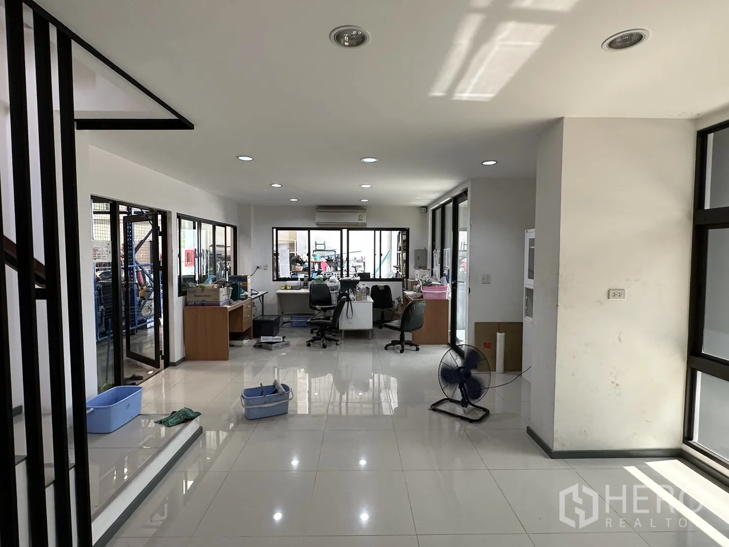 Factory for rent or sale in Pathum Thani - Bright office workspace with desks and glass doors to the warehouse.