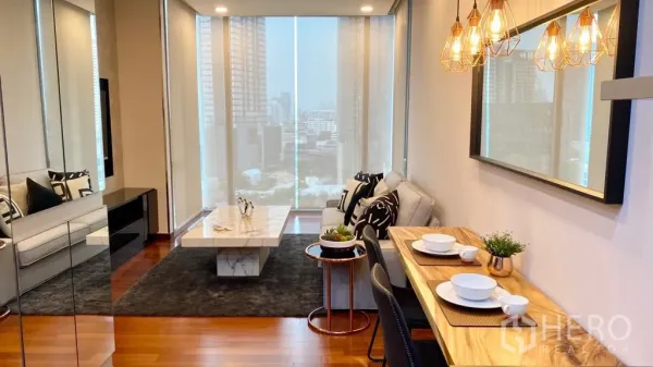 Condominium for sale in Khlong Toei, Bangkok - Bright living and dining area with pendant lights, marble coffee table and skyline views through floor‑to‑ceiling windows.
