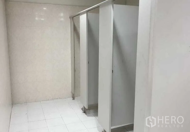 Warehouse for rent in Mueang Samut Prakan, Samut Prakan - Tiled restroom inside the facility with partitioned toilet stalls.