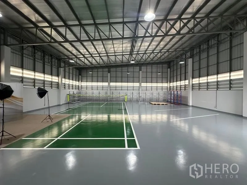 Warehouse for sale in Pathum Thani - High-ceiling warehouse with epoxy floor and marked multi-purpose court under a steel truss roof.