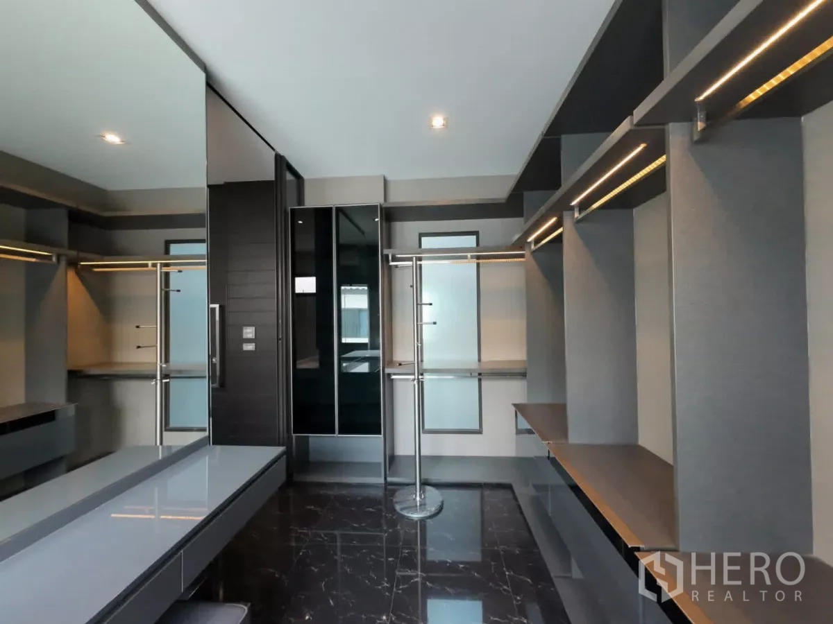 Townhouse for rent or sale in Lat Phrao, Bangkok - Luxury walk-in wardrobe with dark marble floor and large mirror.