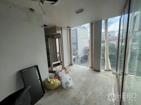 Retail Space for rent in Bang Rak, Bangkok - Upper-floor interior with floor-to-ceiling windows and unfinished floors overlooking the neighborhood.