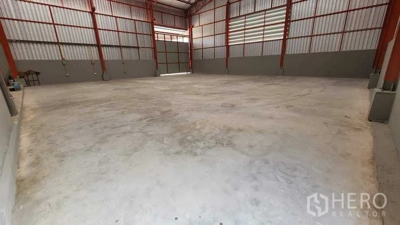 Warehouse for rent in Nong Chok, Bangkok - Open warehouse floor with high clear span, concrete slab, and a roller door at the end.