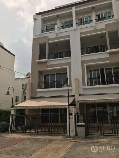 Townhouse for rent or sale in Bang Kho Laem, Bangkok - Four-storey townhouse exterior with white facade, balconies, awning and gated front patio.