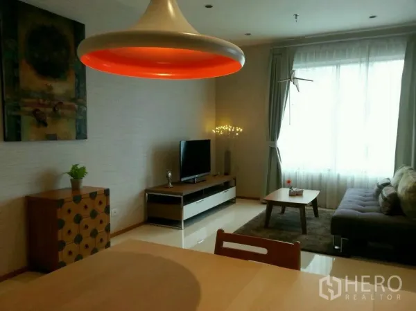 Condominium for rent or sale in Khlong Toei, Bangkok - Bright living room with large window, gray sofa, TV unit and bold pendant light.