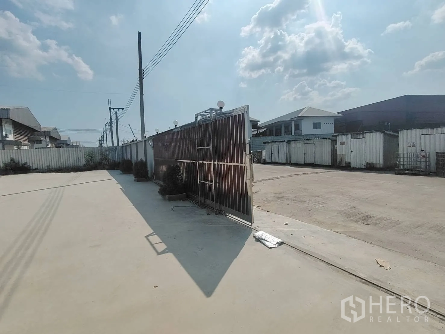 Warehouse for rent in Bang Phli, Samut Prakan - Large paved yard inside a gated compound with boundary wall and utility poles.