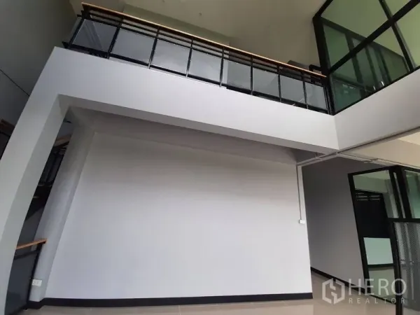 Factory for rent or sale in Lam Luk Ka, Pathum Thani - Interior mezzanine area with high ceiling and black metal railing.