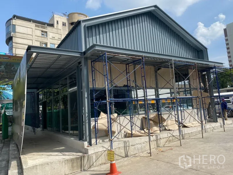 Retail Space for rent in Khlong Toei, Bangkok - Side view of new retail unit with canopy roof, floor-to-ceiling windows and scaffolding, with wide forecourt access suitable for customers and deliveries.