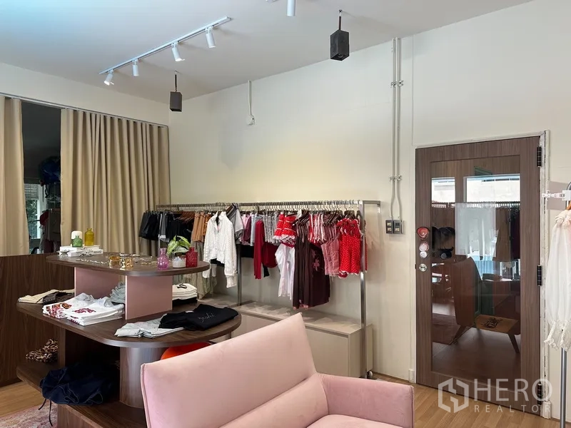 零售空间 for rent in Khlong Toei, Bangkok - 店内摆放衣架与粉色沙发，中央展示台与轨道灯，配玻璃门。
