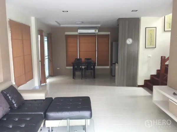Detached House for sale in Lat Krabang, Bangkok - Open-plan living and dining area with sofa set, tiled floors, air conditioner and staircase.