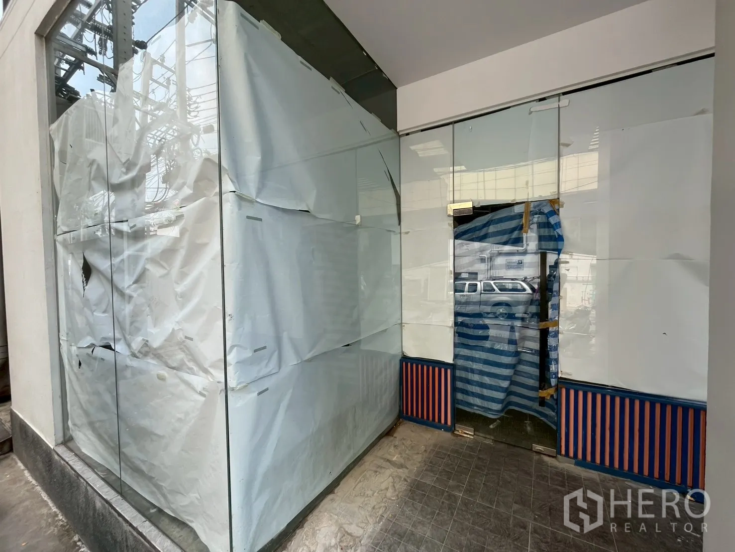 พื้นที่ขายของ for rent in Watthana, Bangkok - ยูนิตหัวมุมกระจกเต็มบาน ประตูกระจกปิดเทป ติดทางเดินปูหิน มองเห็นเสาและสายไฟด้านนอก