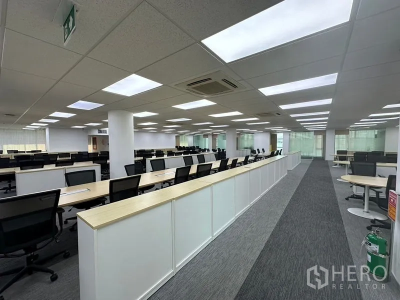 办公空间 出租 - 大型工位区，成排办公桌与座椅，顶部LED灯板。