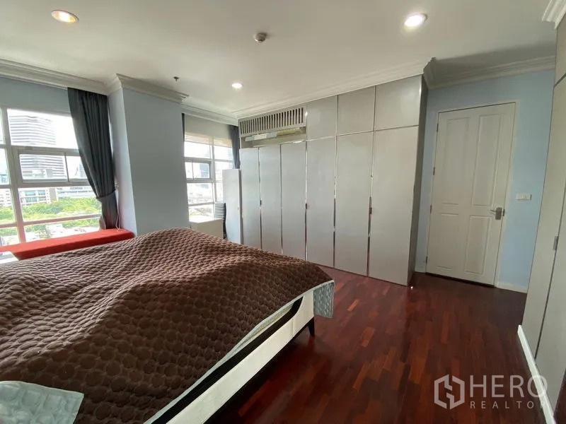 Condominium for rent in Ratchathewi, Bangkok - Corner master bedroom with city-view windows and full-height wardrobes.