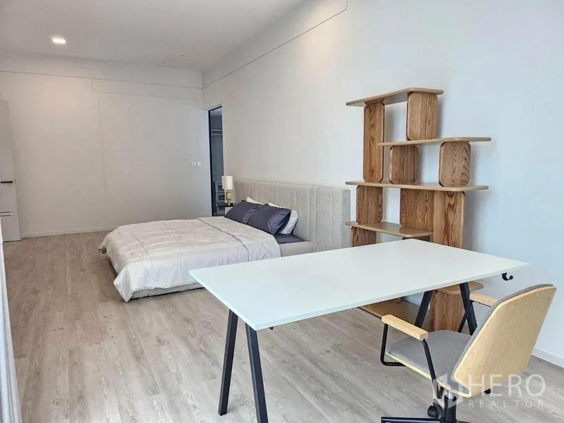 Detached House for rent - Bright bedroom view showing a study desk, chair and open wooden shelf beside the bed.