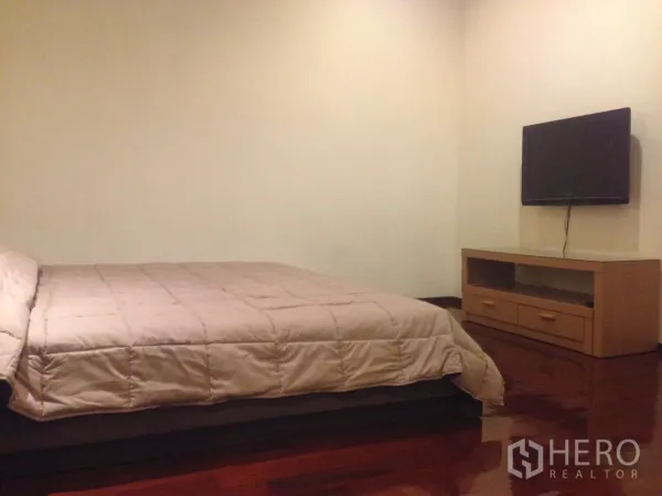 公寓 出租在Watthana, Bangkok - 卧室配大床，墙挂电视与木质电视柜，实木地板光泽亮丽。