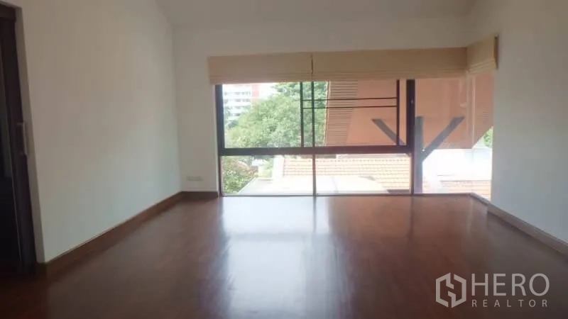 Detached House for rent in Watthana, Bangkok - Upper-floor bedroom with wide window, blinds, and views over trees and rooftops.