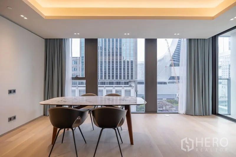 Condominium for rent in Pathum Wan, Bangkok - Close view of dining area beside panoramic windows and modern city architecture.