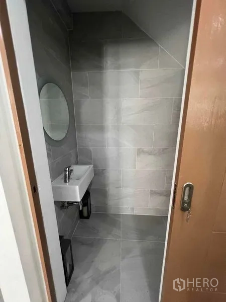 联排别墅 出租在Khlong Toei, Bangkok - 楼梯下的小型盥洗室，圆镜与小洗手盆。