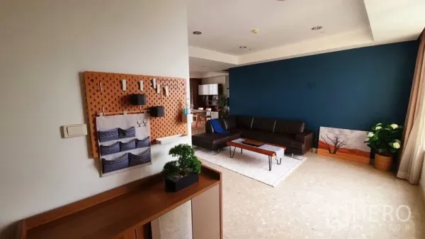 Condominium for rent in Watthana, Bangkok - Lounge with brown leather sofa, blue feature wall, pegboard storage and wide window.