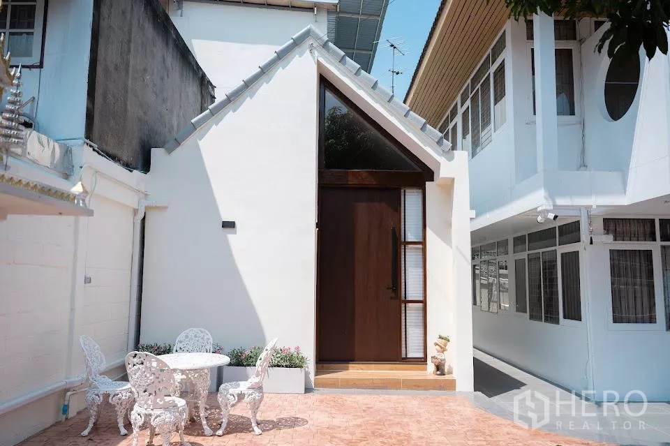 Detached House for rent in Phra Khanong, Bangkok - Close-up of the house’s modern white facade and entrance door by the courtyard.