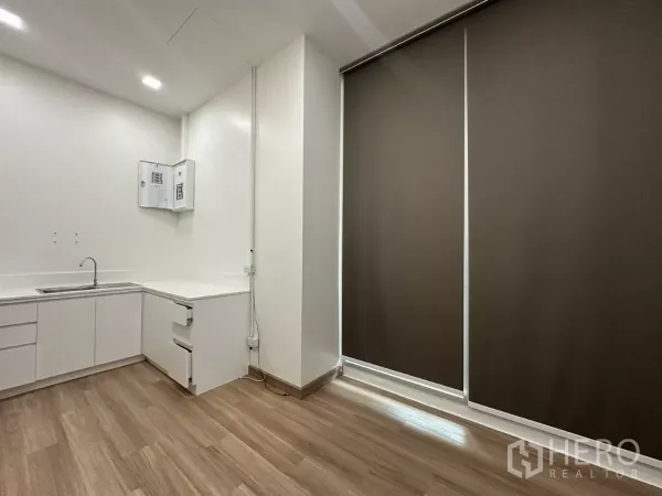 Retail Space for rent in Phra Khanong, Bangkok - Compact prep room with white cabinetry, sink and wood flooring beside full‑height roller blinds.