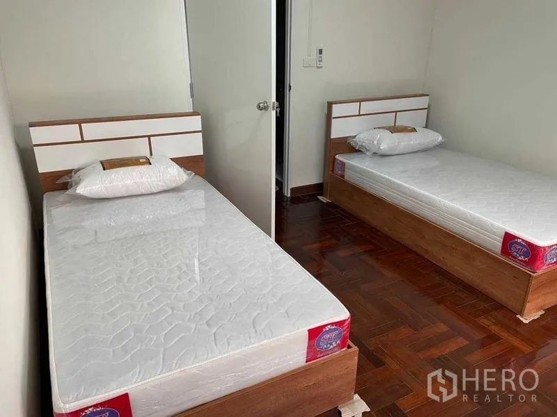 带办公室的家 出租或出售在Watthana, Bangkok - 第二间双单人床卧室，白墙与木地板。