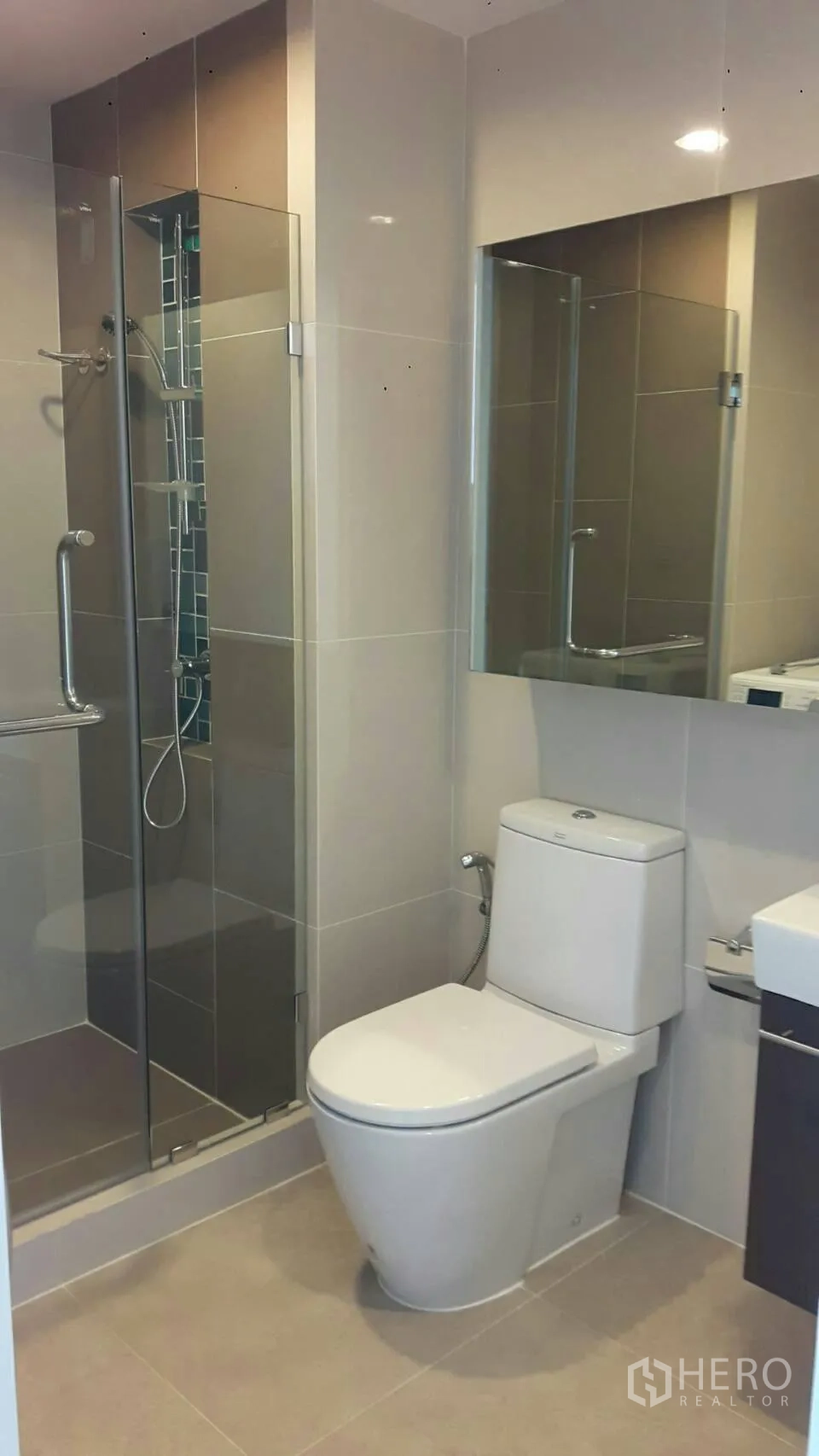 Condominium for rent in Phaya Thai, Bangkok - Contemporary bathroom with glass-enclosed shower, vanity and toilet in neutral tiles.
