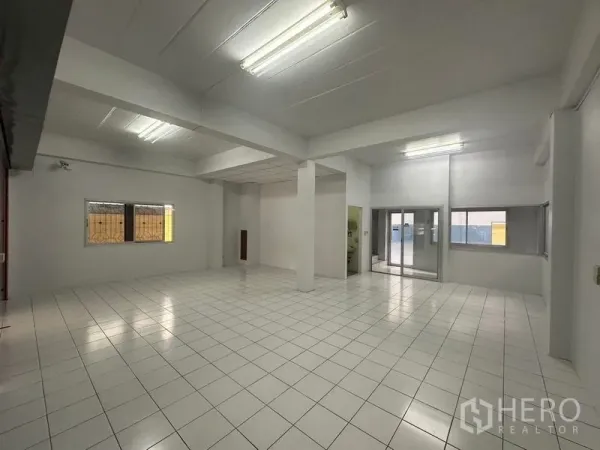 Factory for rent in Pathum Thani - Open-plan white interior with ceiling lights and ceramic tile flooring.
