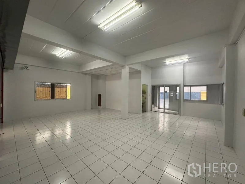 Factory for rent in Pathum Thani - Open-plan white interior with ceiling lights and ceramic tile flooring.