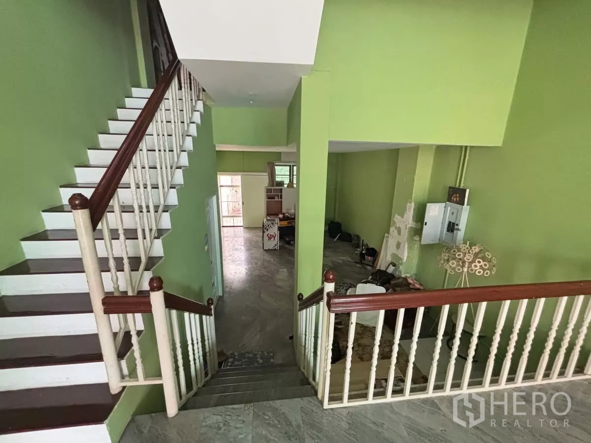 Shophouse for rent in Watthana, Bangkok - View from the stair landing over the open-plan level with green walls and railings.