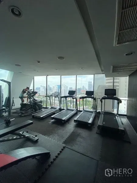 Condominium for rent or sale - Condominium fitness room with treadmills and city skyline views through floor-to-ceiling windows.