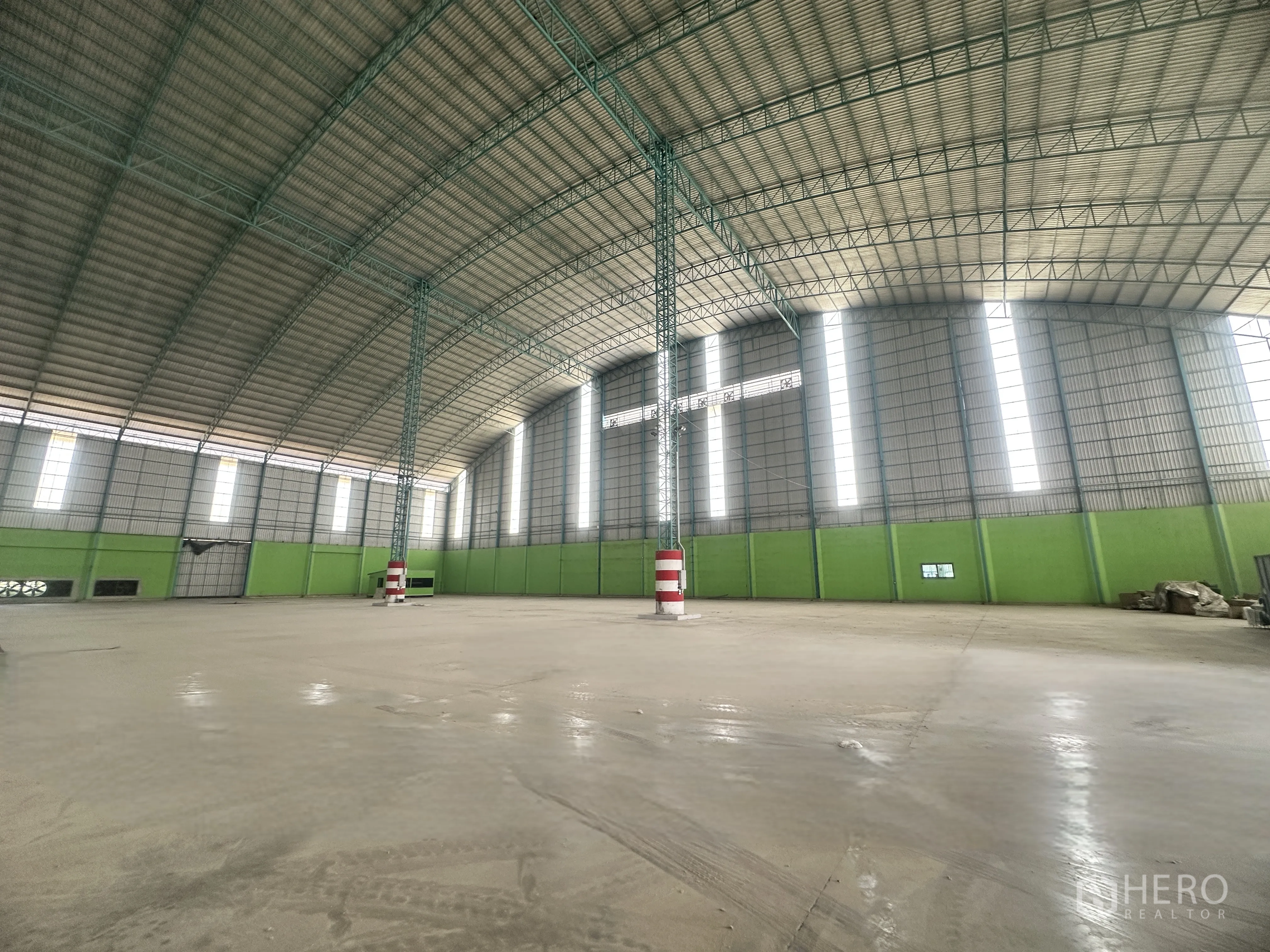 Warehouse for rent in Sai Noi, Nonthaburi - Spacious warehouse interior with high truss roof, vertical daylight panels, and clear open floor area.