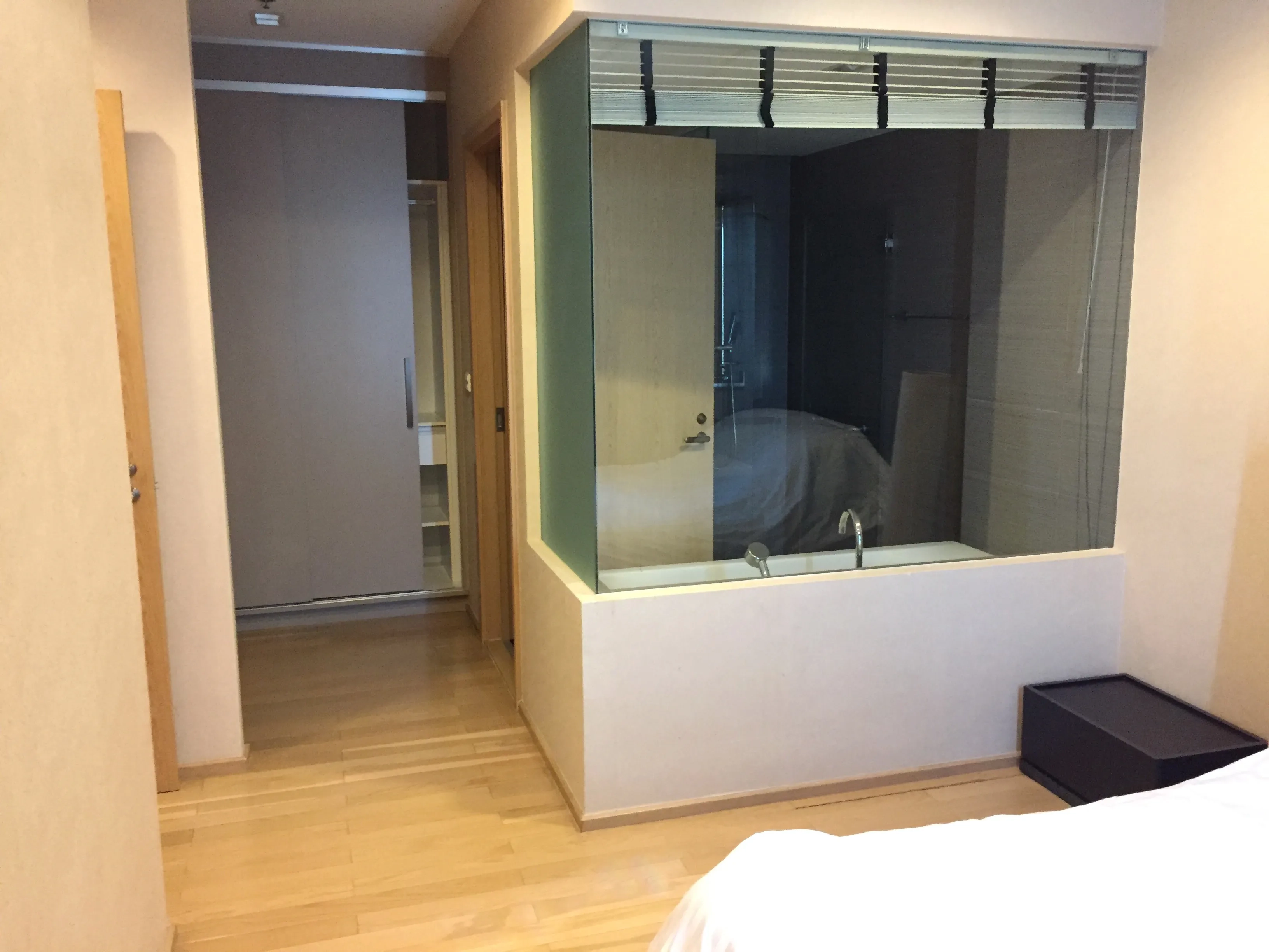 Condominium for rent in Khlong Toei, Bangkok - Master suite corridor with built‑in wardrobe and glass wall bathroom featuring a soaking tub.
