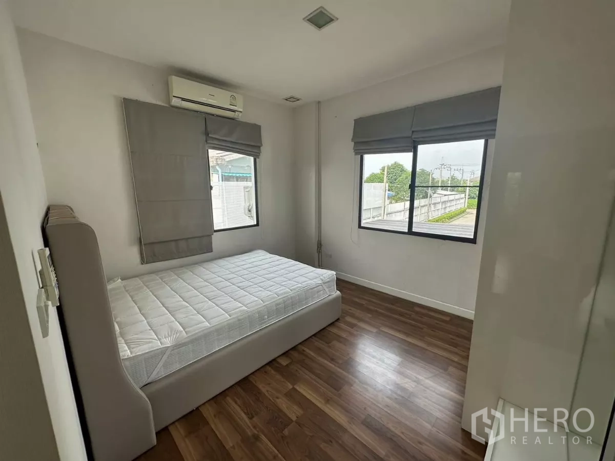 Detached House for rent or sale in Bang Kapi, Bangkok - Airy secondary bedroom with large windows, wood flooring and air conditioning.