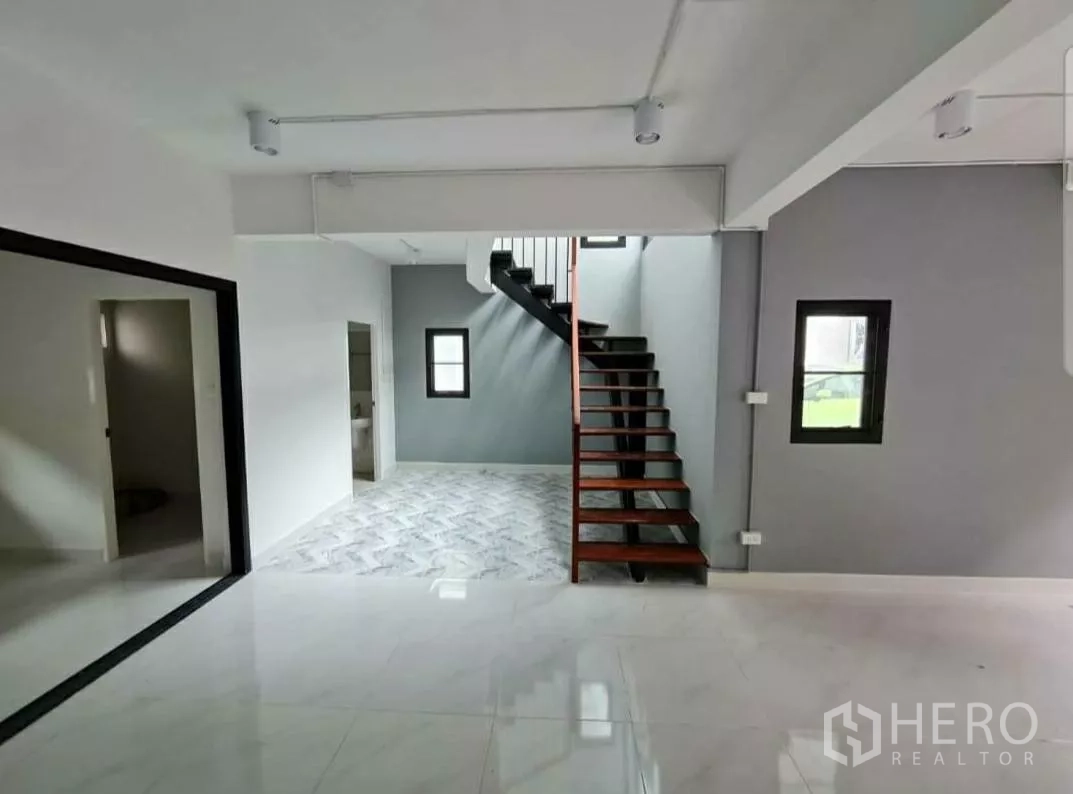 带办公室的家 出租在Lat Phrao, Bangkok - 木踏步楼梯配灰色特色墙与仿石纹地面。