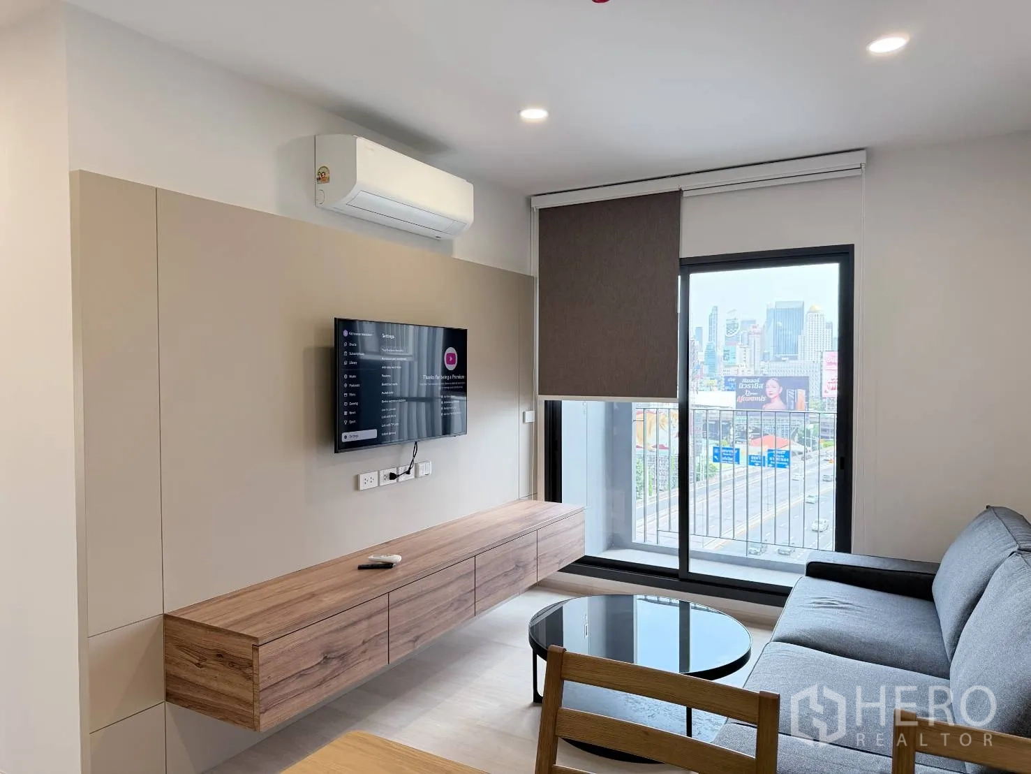 公寓 for rent in Din Daeng, Bangkok - 舒适客厅内有悬浮电视柜、卷帘，外侧可见阳台栏杆。