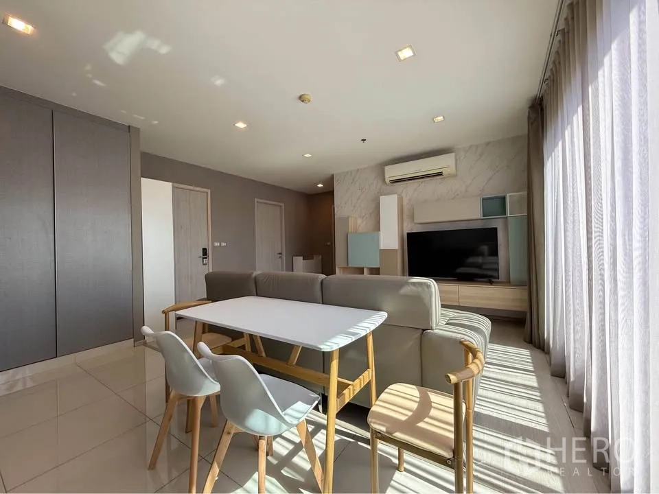 公寓 for rent in Khlong Toei, Bangkok - 客餐厅一体，设沙发、四人餐桌与媒体墙，旁为高窗。