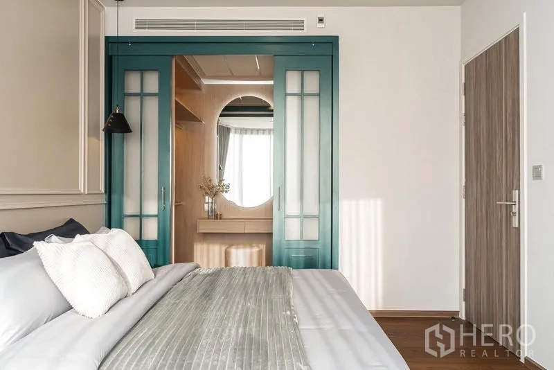 Condominium for rent in Khlong Toei, Bangkok - Bright bedroom with king bed, teal doors, and classic panel wall details.