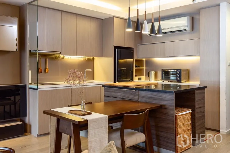 Condominium for rent in Watthana, Bangkok - Contemporary kitchen with wood cabinetry, island countertop, pendant lighting, and built-in appliances.