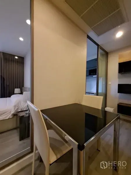 Condominium for rent in Bang Rak, Bangkok - Compact dining area with black-glass table beside sliding glass partition to bedroom.