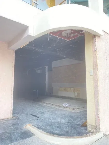 Retail Space for rent in Watthana, Bangkok - Street-facing retail unit with arched entrance and unfinished interior with dark ceiling and tiled floor.
