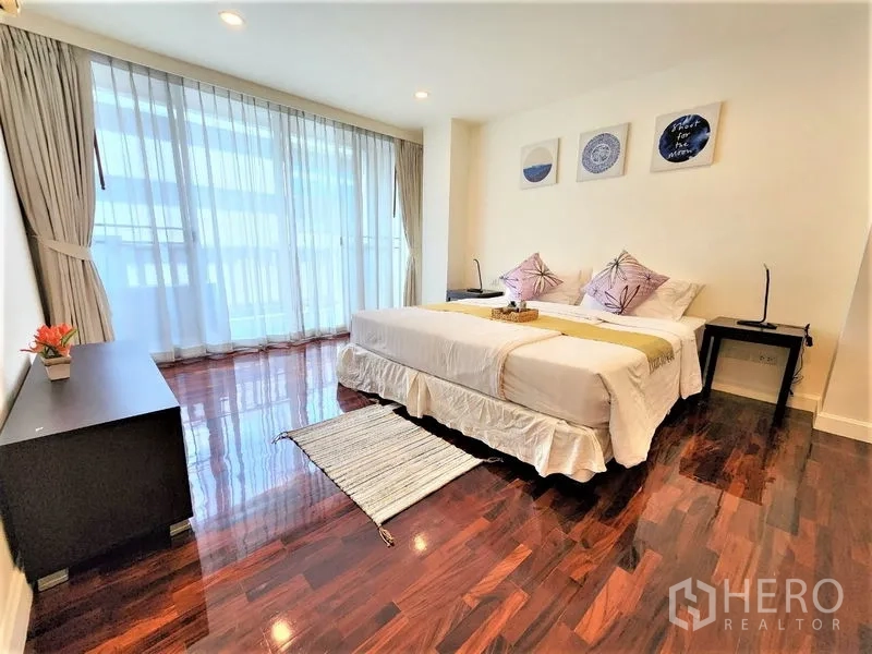 Condominium for rent in Bang Rak, Bangkok - Bright Silom Bangkok condo bedroom with floor-to-ceiling windows, sheer curtains and glossy hardwood floors.